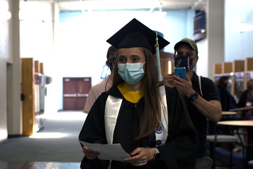 Image of a 2020 graduate holding a paper