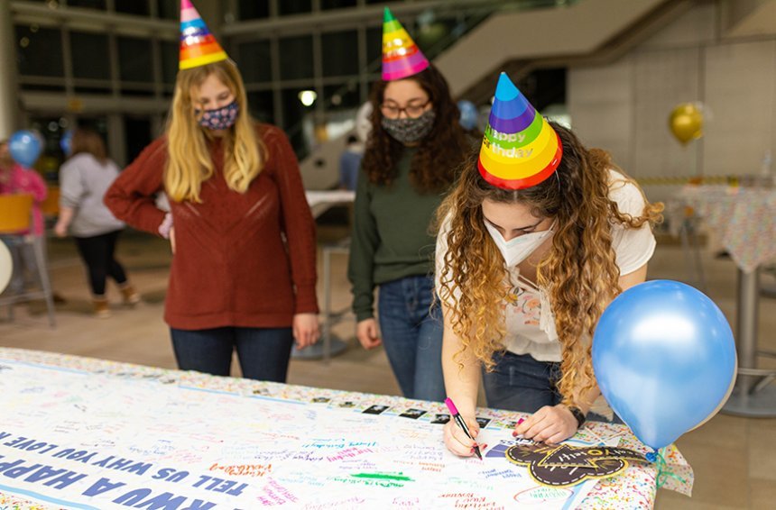 image of students signing a banner wishing Roger HBD