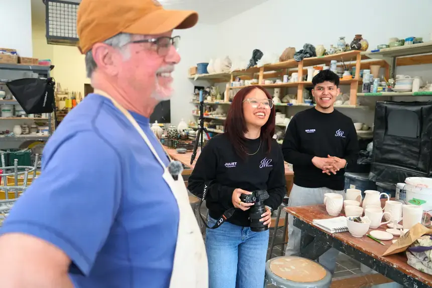Denis Leonti, Juliet Garcia-Baez, and Wilder laugh together inside the clay studio.