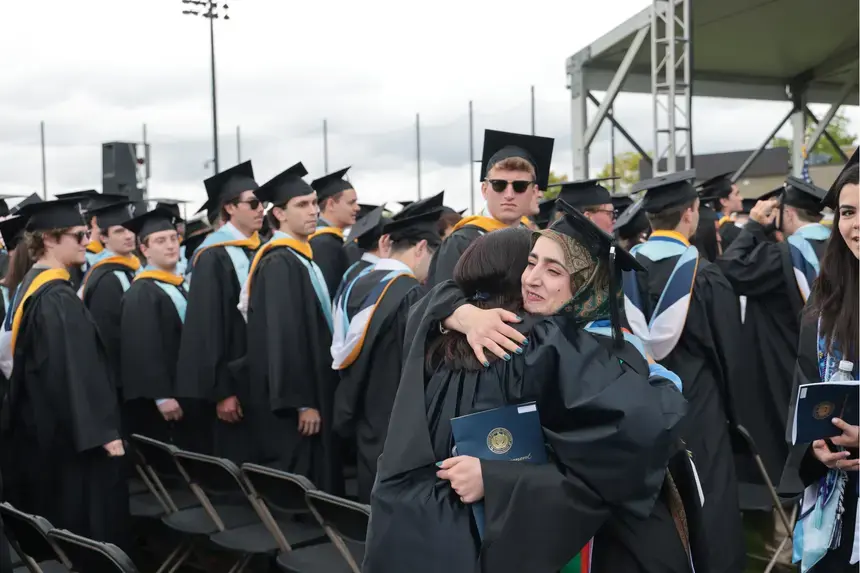 Graduate student speaker Abida Mohammady gets a hug following her speech.