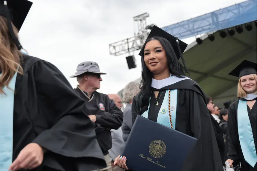 A graduate departs the Commencement main ceremony with diploma in hand.