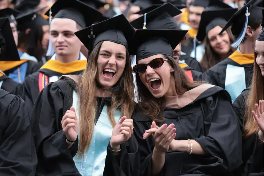 Two graduates cheer in excitement.