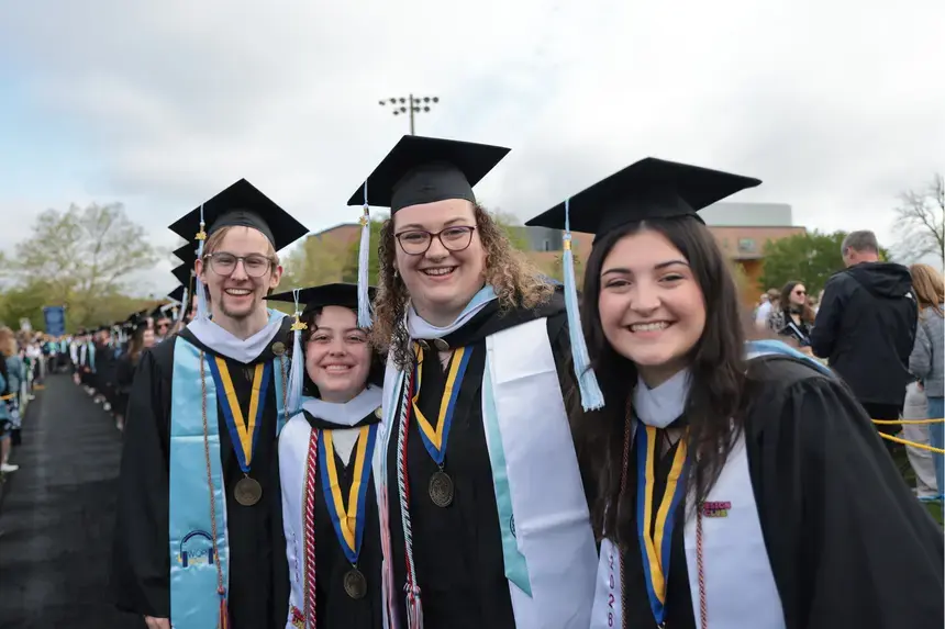 Graduates pose down the center aisle at the Commencement main ceremony on the Paolino Field.