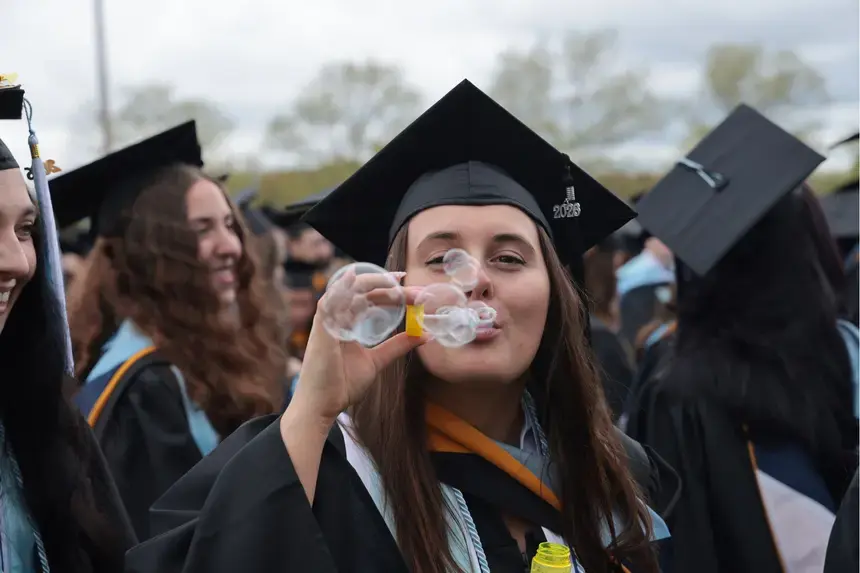 A graduate blows bubbles during the Commencement main ceremony.
