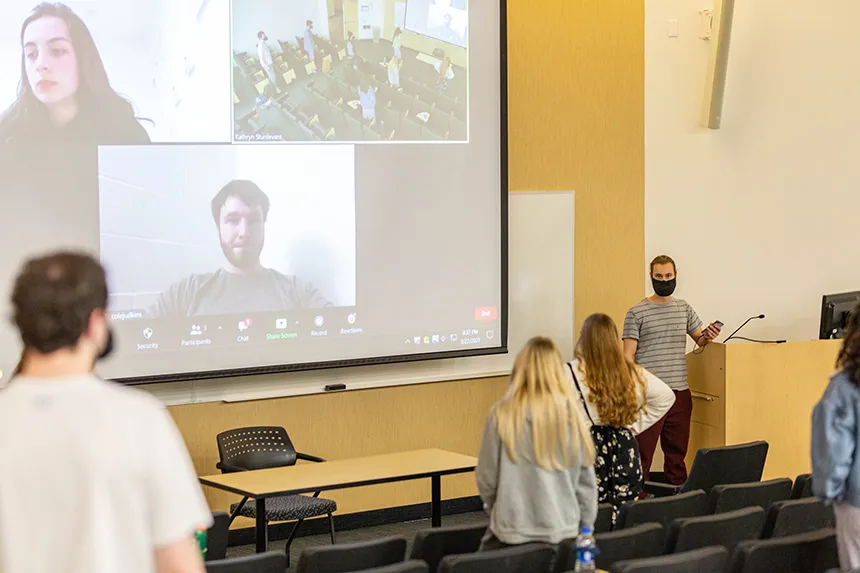 image of some member of Hawkward projected on a big screen, joining practice remotely