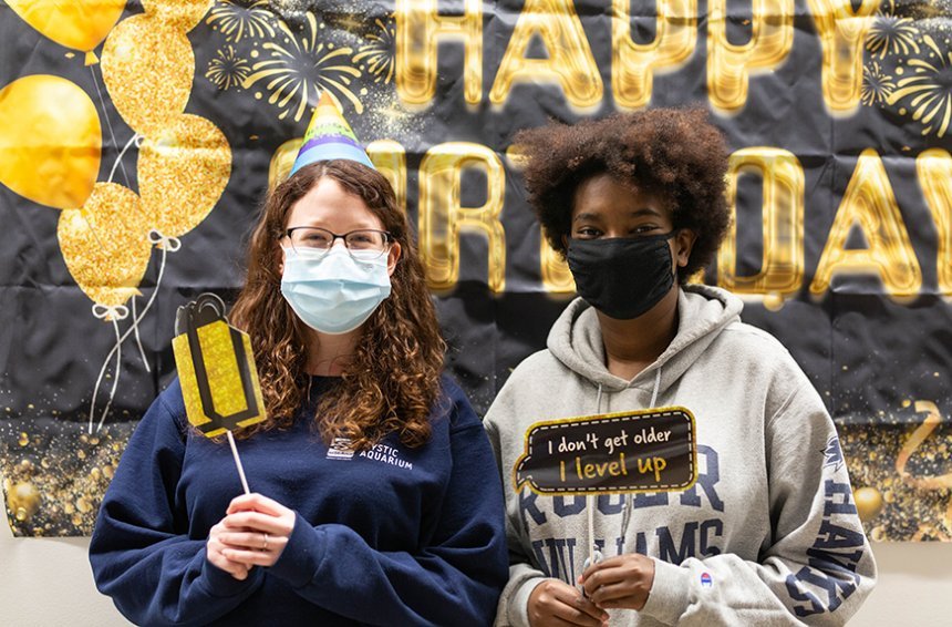 image of two students posing with props to get their photos taken in front of Happy Birthday banner