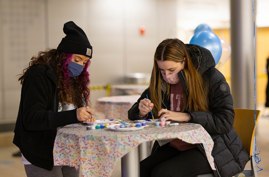 image of two seated masked students working on a craft project at the birthday party for Roger