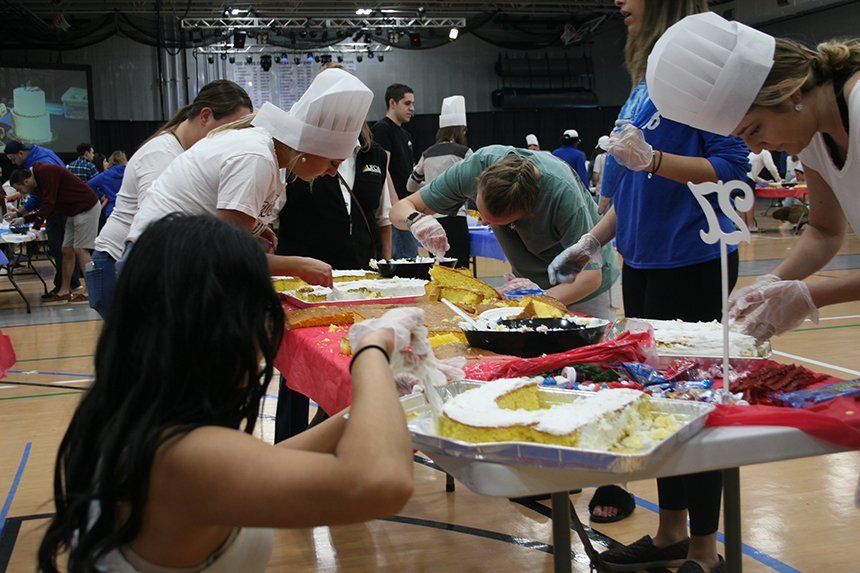 Group of students decorating a cake.