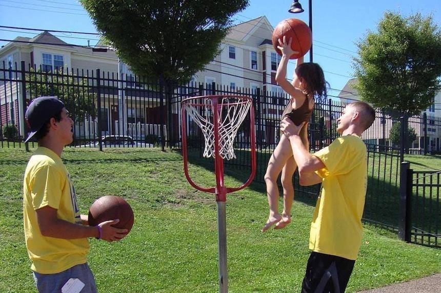 Two freshmen students playing basketball with young girl.