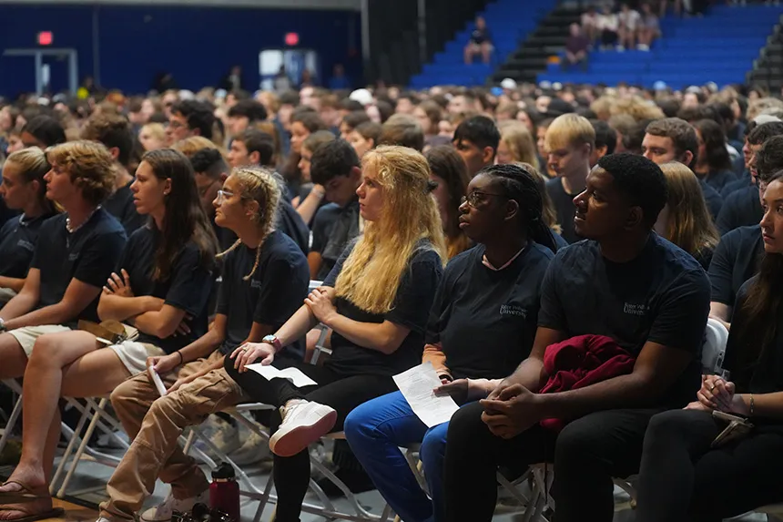 Students sitting in a row and looking at the stage, listening to speeches