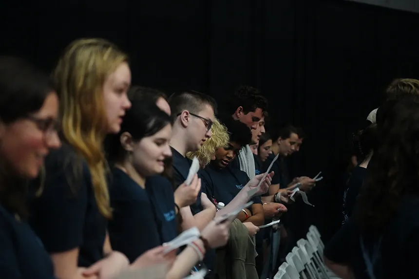 A row of students standing and reciting the academic pledge 