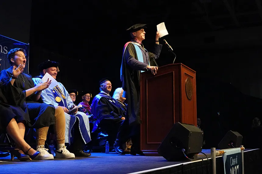 Jeffrey Meriwether standing at a podium, holding a piece of paper 
