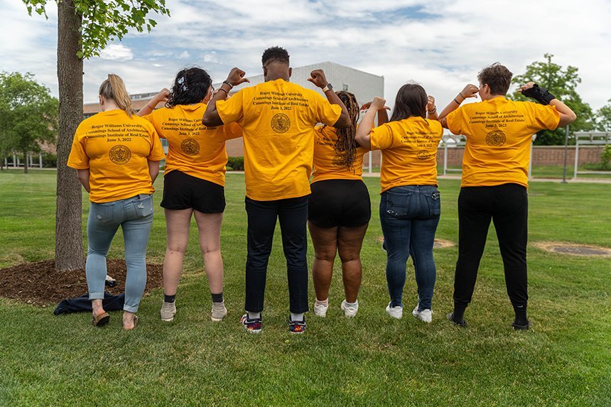 A group of six students showing off the back of their t-shirts that read Cummings School of Architecture