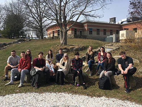 A class of students sit outdoors on Bristol Campus