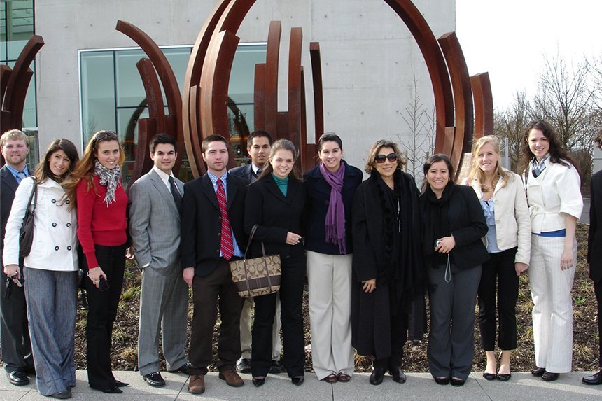 A group of students stand in front of a large sculpture