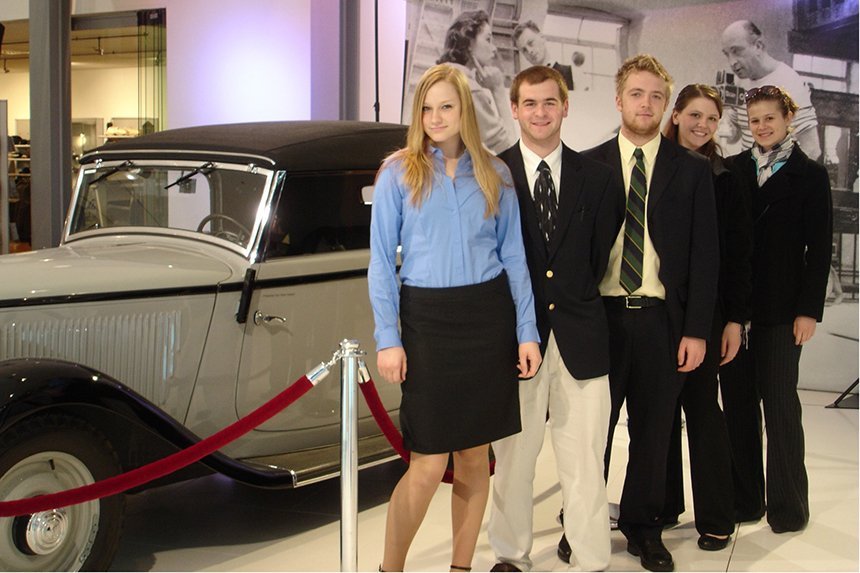 Students stand in front of a car
