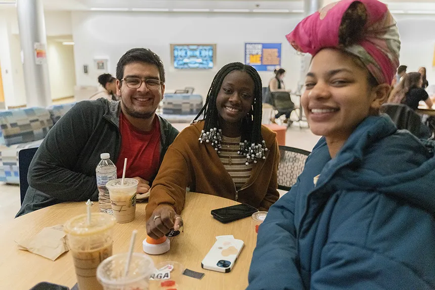 Three students sitting around a table during a Jeopardy-style game held in GHH.