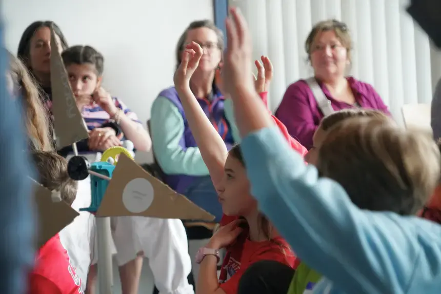 Fourth graders raise their hands at the Celebration Event.
