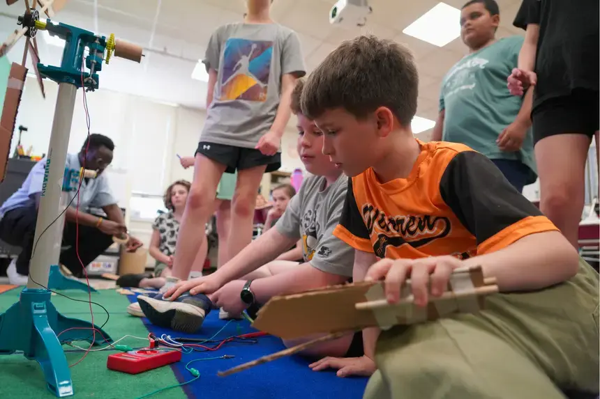 Fourth graders at Hugh Cole Elementary School look at their multimeter as their wind turbine is put to the test.