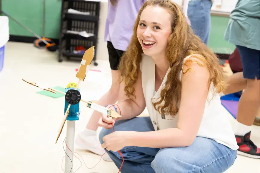Sophomore Mattia McIntyre smiles as she helps fix a wind turbine.