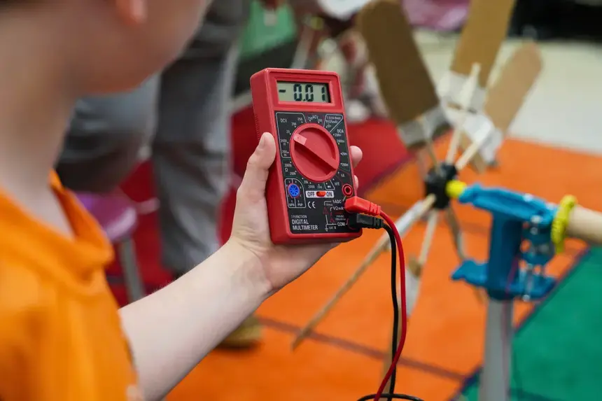 A Hugh Cole Elementary School fourth grader looks at the multimeter as his group tests their wind turbine.