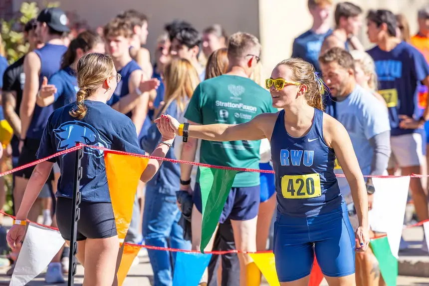 A member of the RWU Cross Country team high-fives a fellow Hawk.