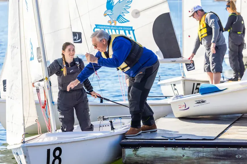 A man climbs onto a sailboat.