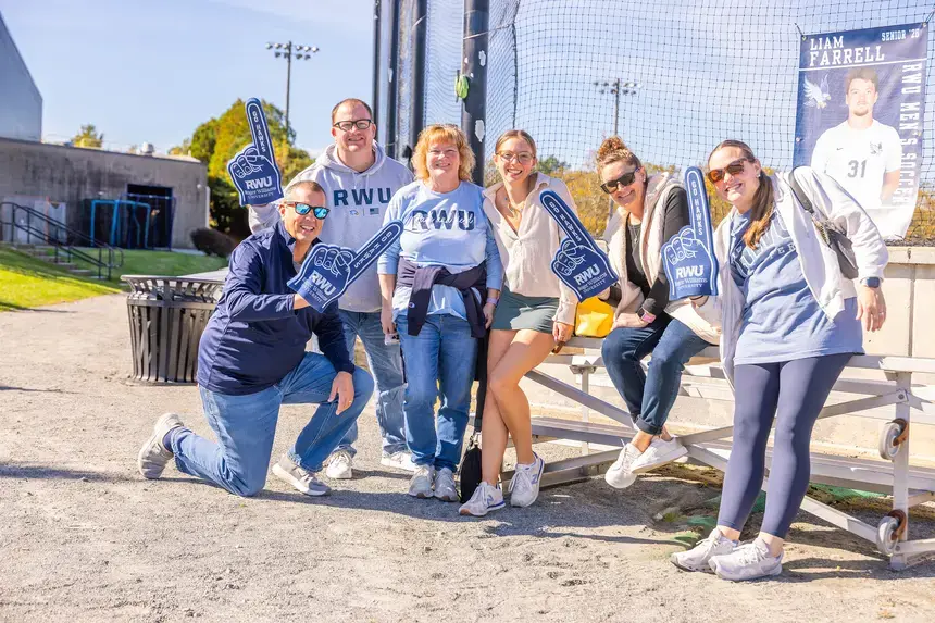 A family poses for a photo while attending an athletic game.