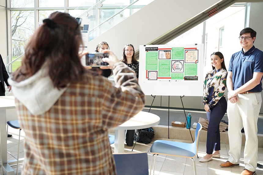 A student taking a photo of a group of student presenters at SASH 