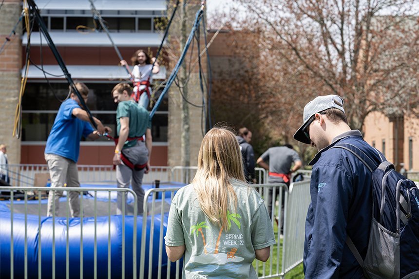 Two students standing with the bungee trampoline in the background. 