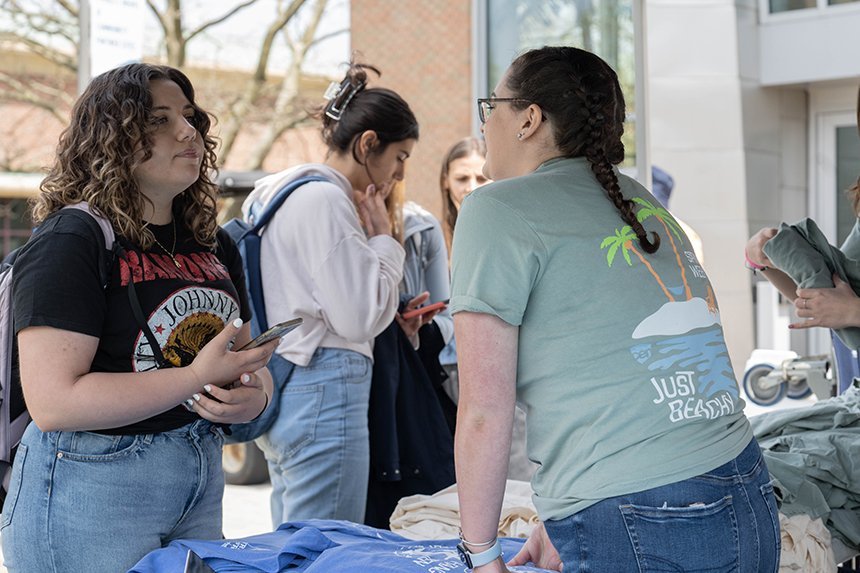 A student talking to a CEN student leader at the T-shirt table. 