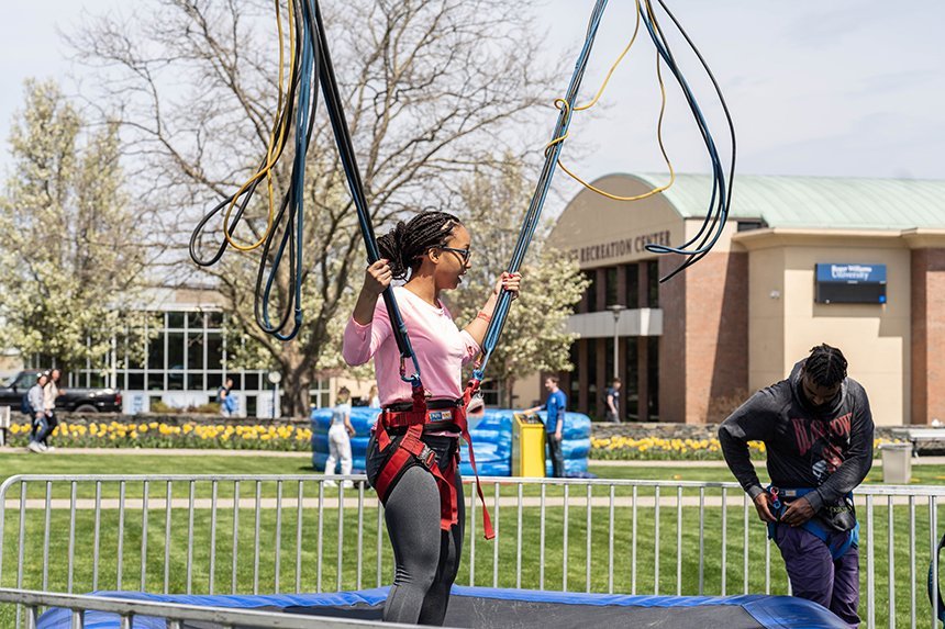 Two students get strapped in to a bungee trampoline activity. 
