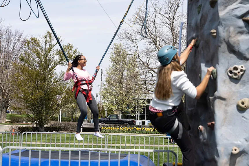 One student on the bungee trampoline and another on the rock-climbing wall.