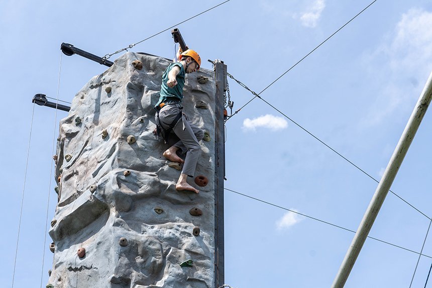 A student at the top of the rock-climbing wall. 