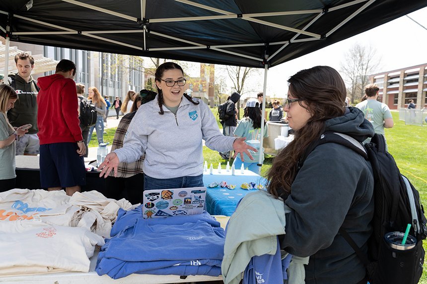 A CEN student leader talks to a student at the T-shirt table. 