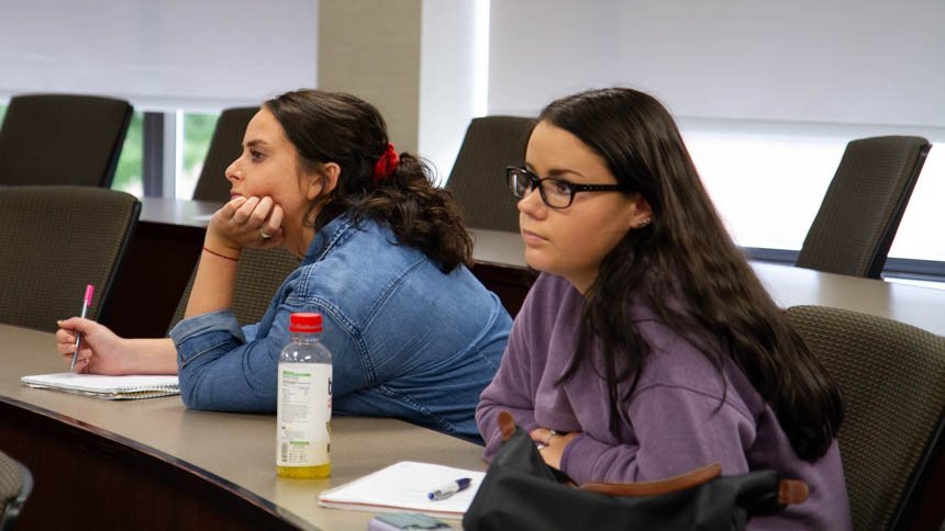 Two students listen to a presentation. 