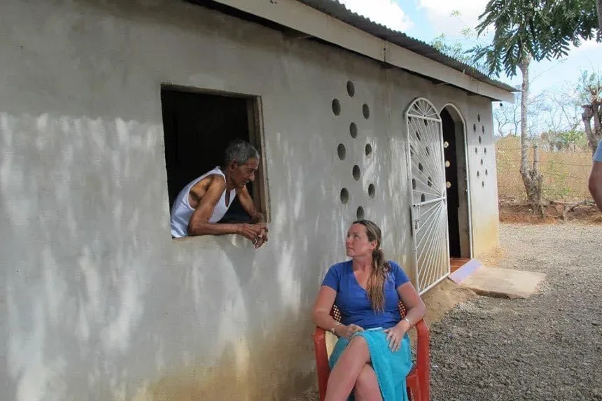 Autumn Quezada-Grant talks with someone through a window of a house