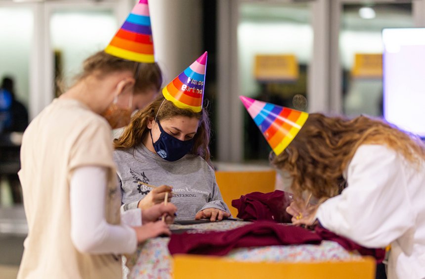 image of three students wearing birthday hats working on a craft project at the party