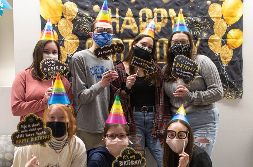 image of a group of masked students posing for a photo in front of the Happy Birthday banner