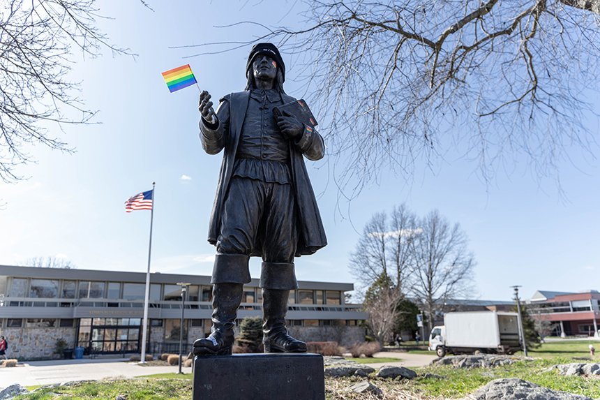The Roger Williams statue holding a rainbow pride flag. 