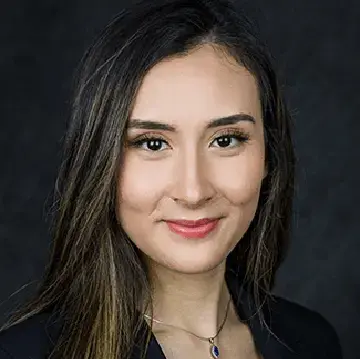Student in a black blazer poses for a professional headshot against a dark background.