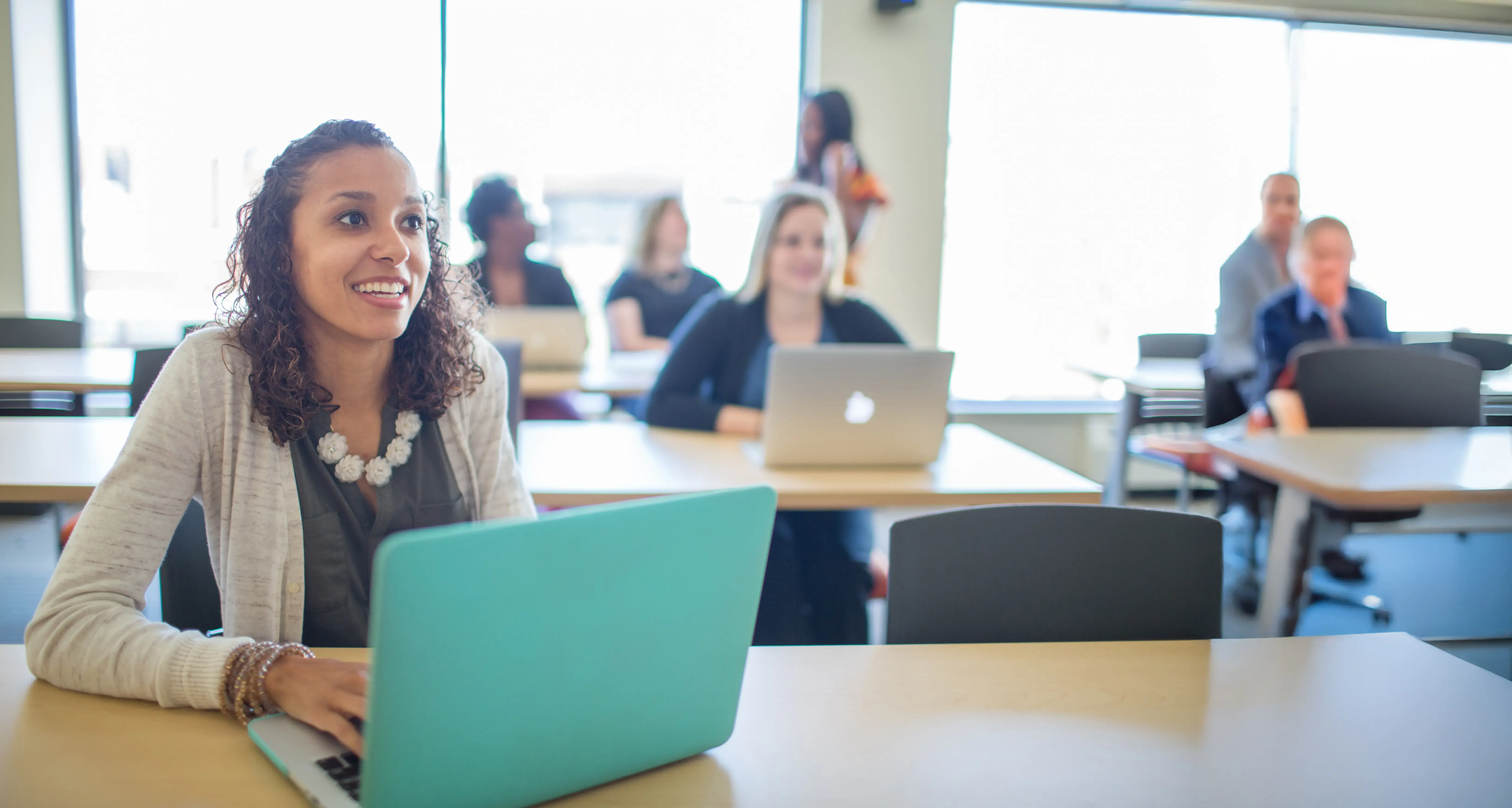 A woman sits in a classrom happy and engaged