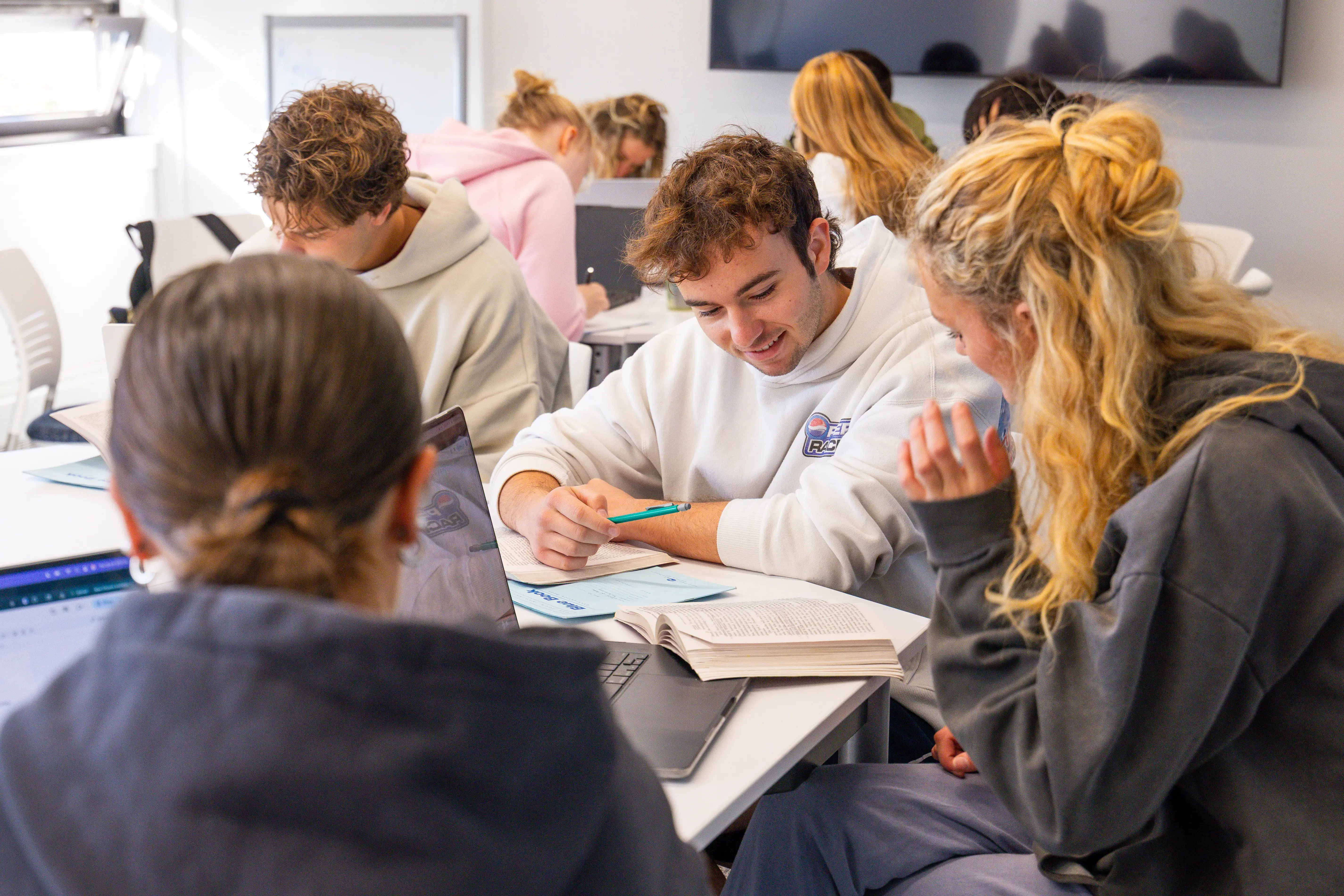 Student work together in pairs to research a Sociology topic in a bright classroom.
