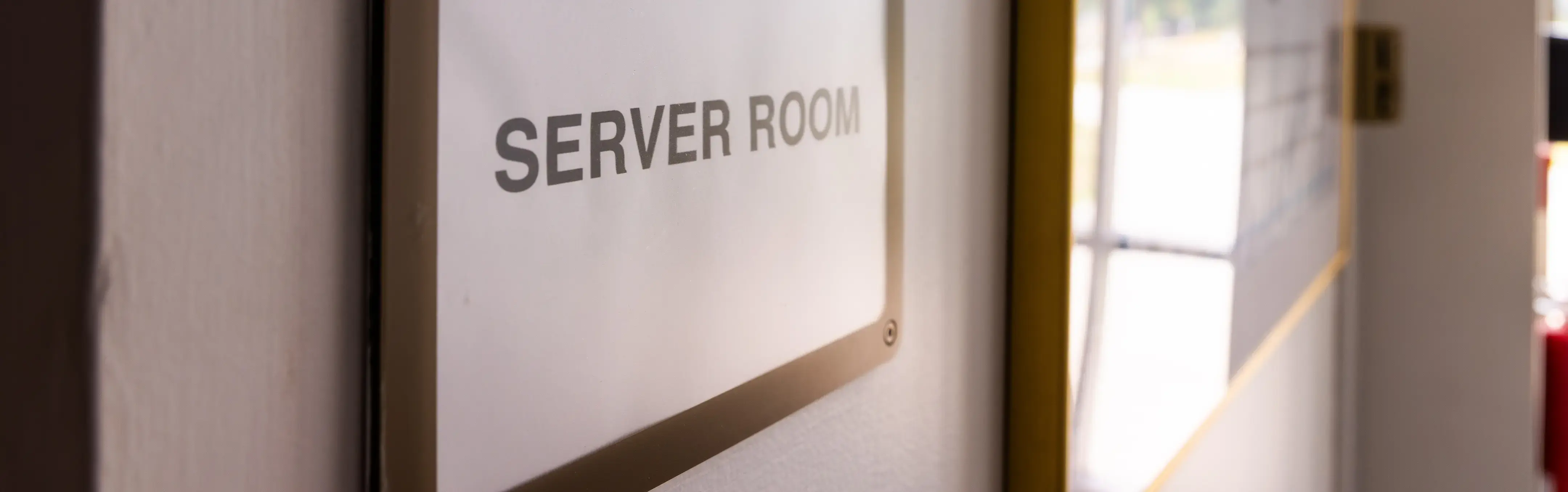A sign to a server room in a dark hallway