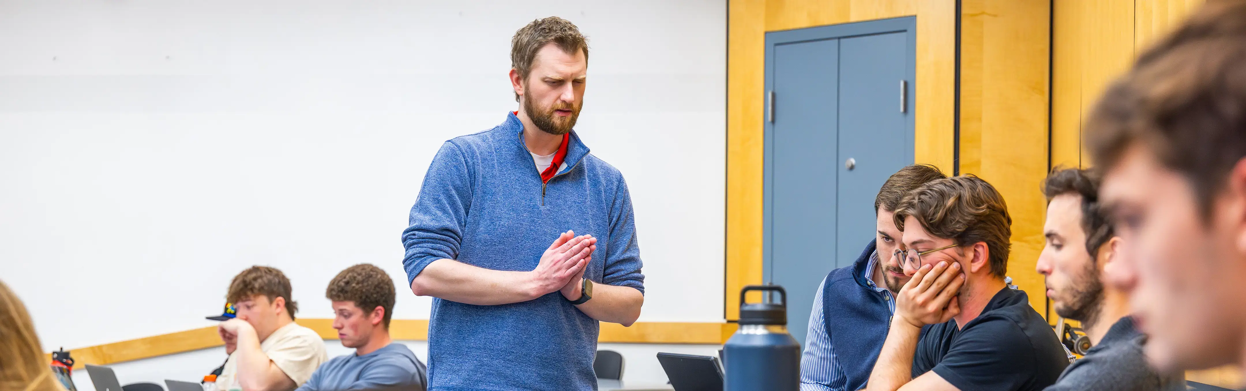 A professor works with students in a classroom