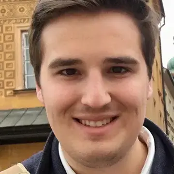 Student smiles in a close-up portrait taken in front of historic architecture.