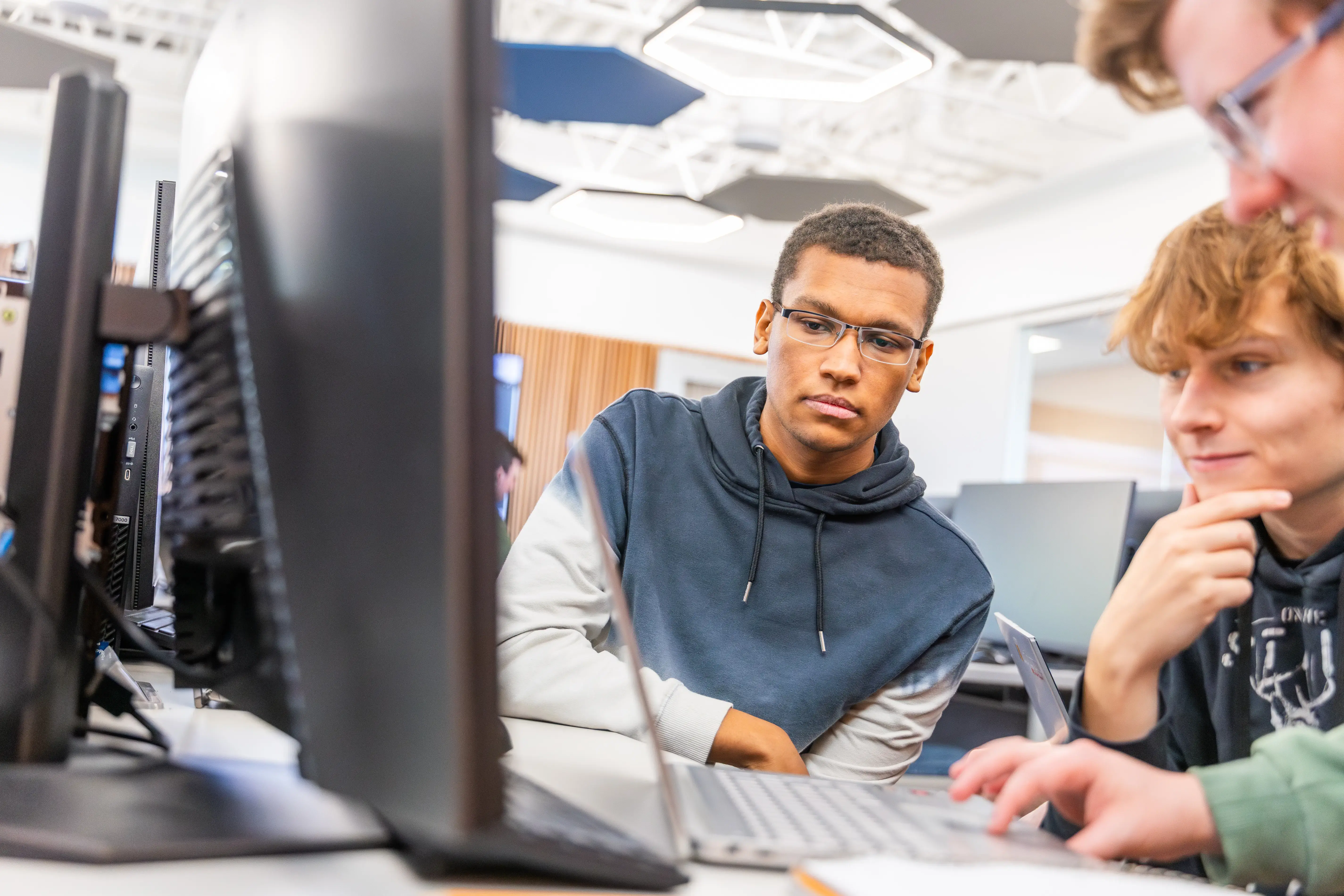 Three students use computers together