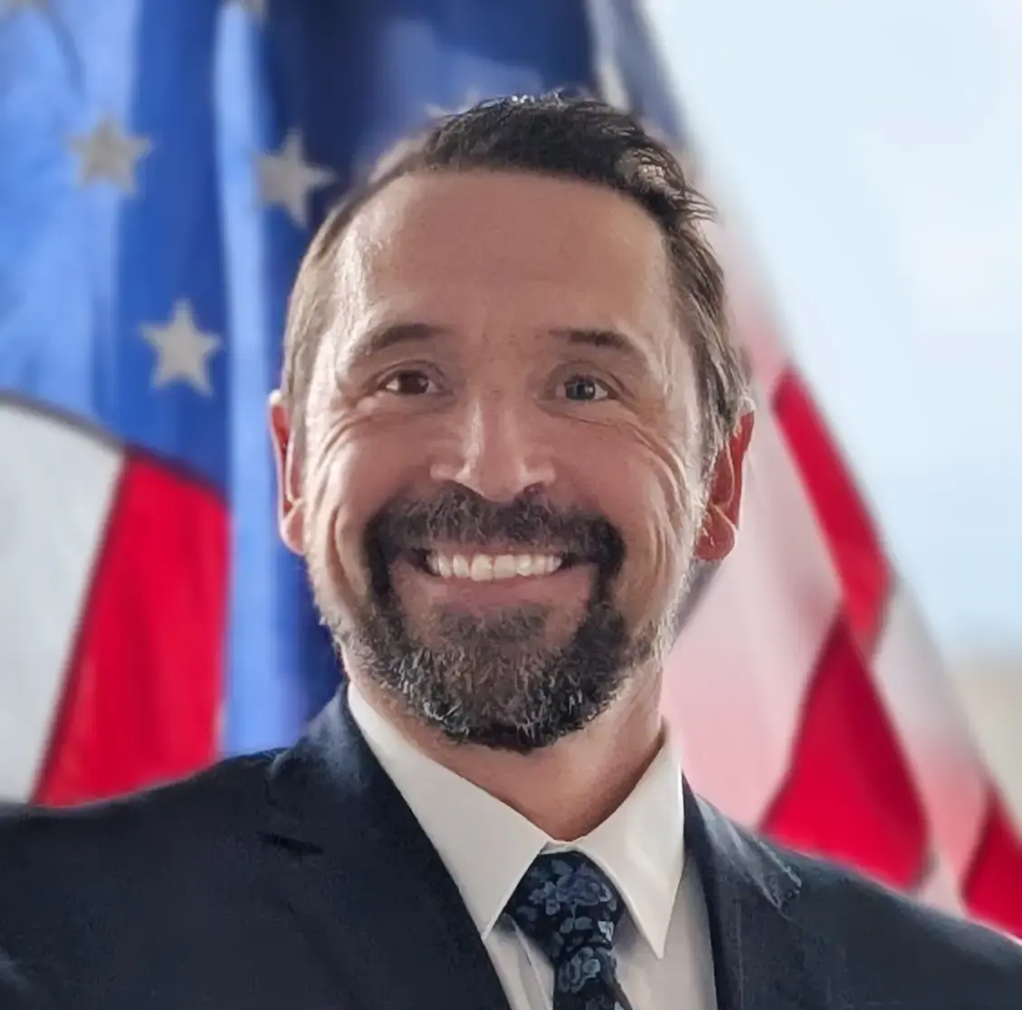 Sean Gorman smiling in front of American flag