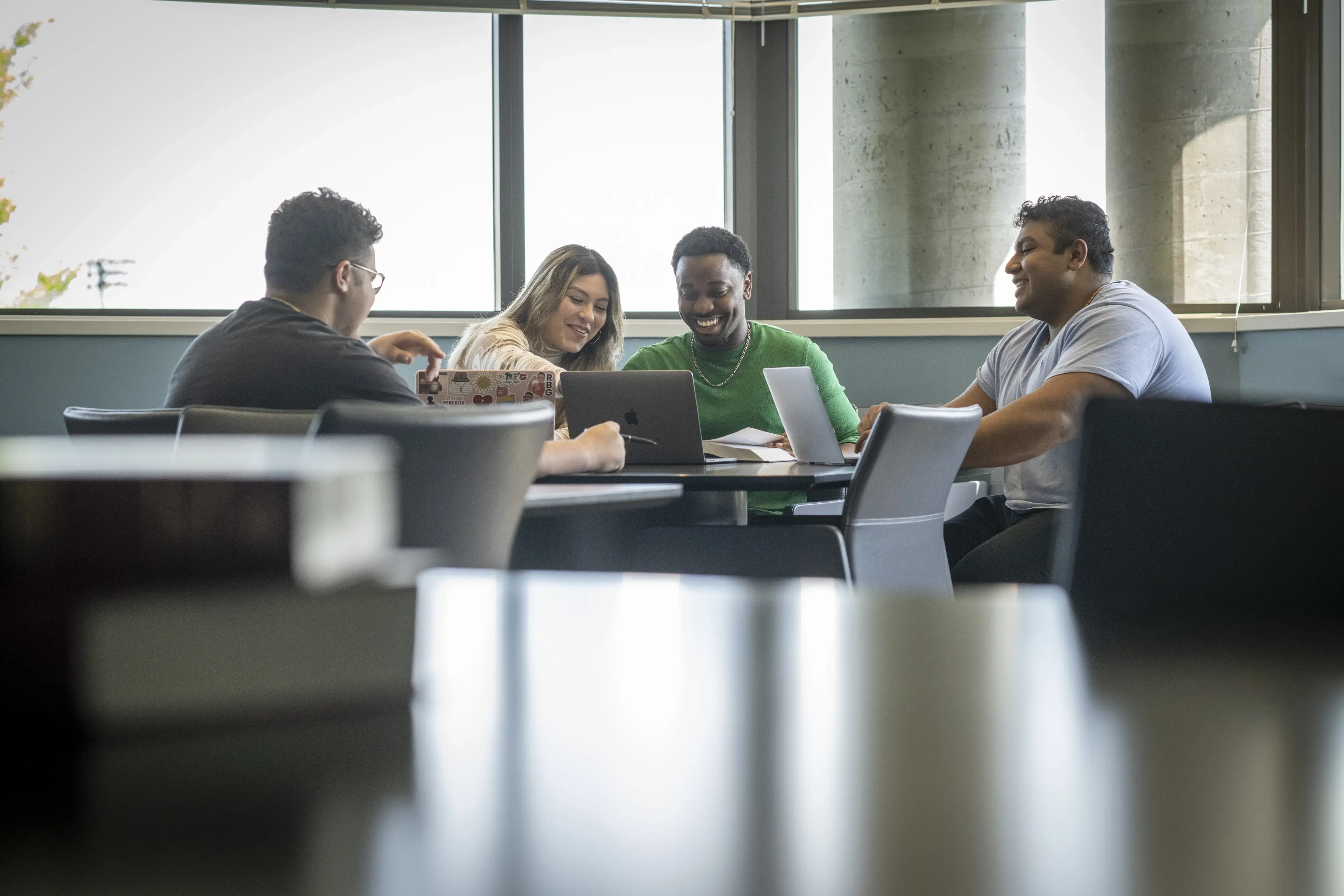 Students smiling around a table collaborating on a project